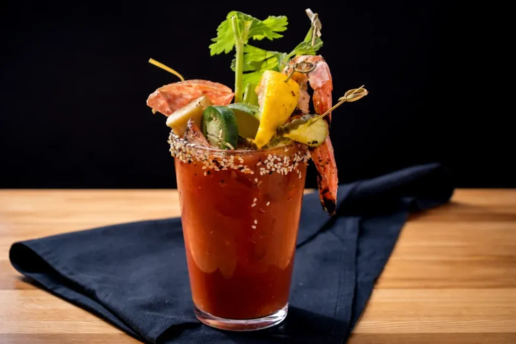 Garnished bloody mary with shrimp, celery and lemon on a bar top at a catered event