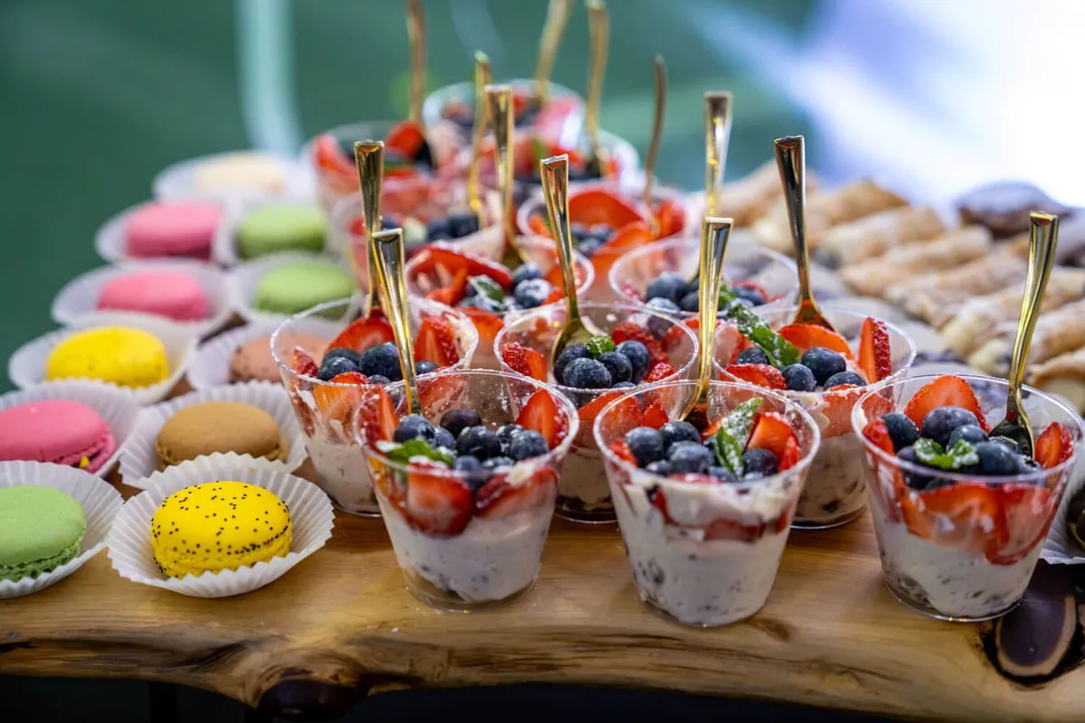 Dessert cups with mixed berries and macarons on a wood board. Catering in Ashburton, Baltimore.