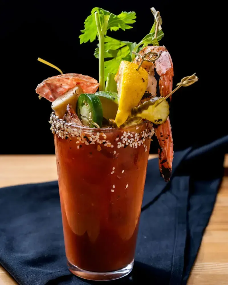 Tall garnished cocktail topped with shrimp and pickled vegetables. Catering in Westport, Baltimore.