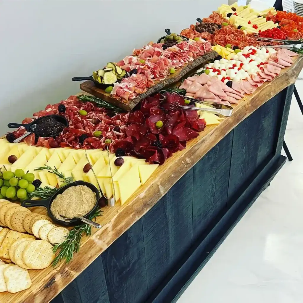 Long grazing table of cured meats, cheeses, crackers and fruit set up for a catered office lunch