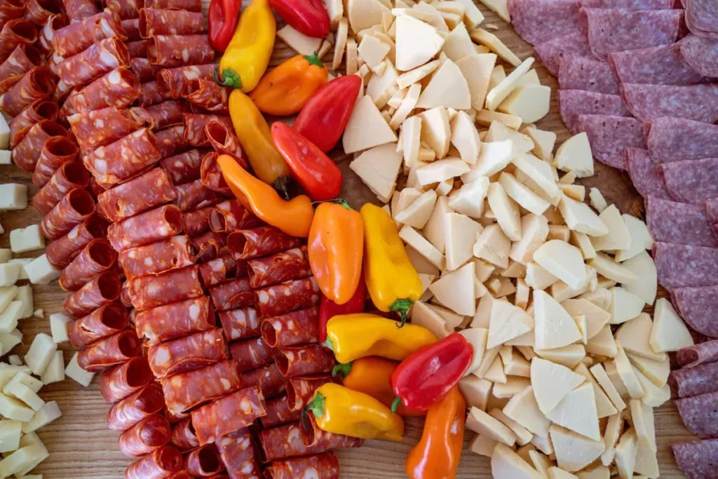 Large shared platter of cured meats, cheeses, and peppers styled for family-style catering service