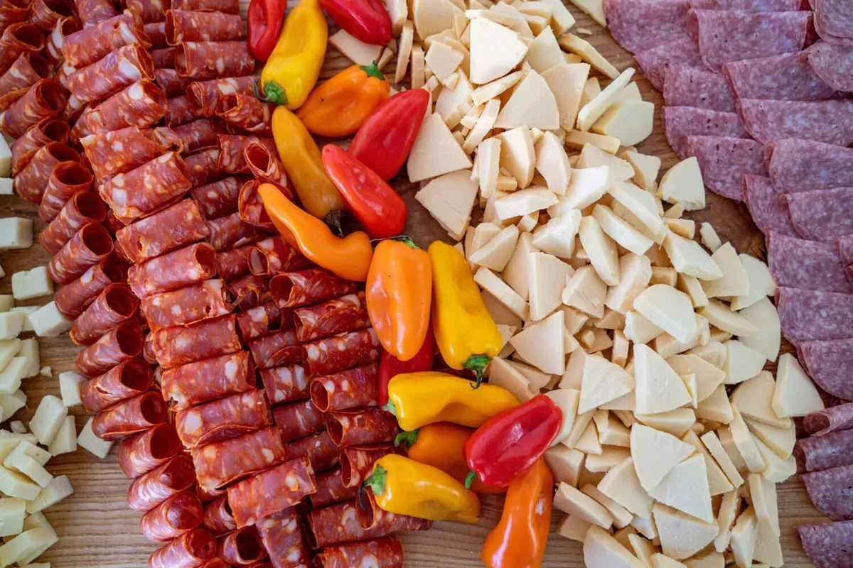 Large shared platter of cured meats, cheeses, and peppers styled for family-style catering service