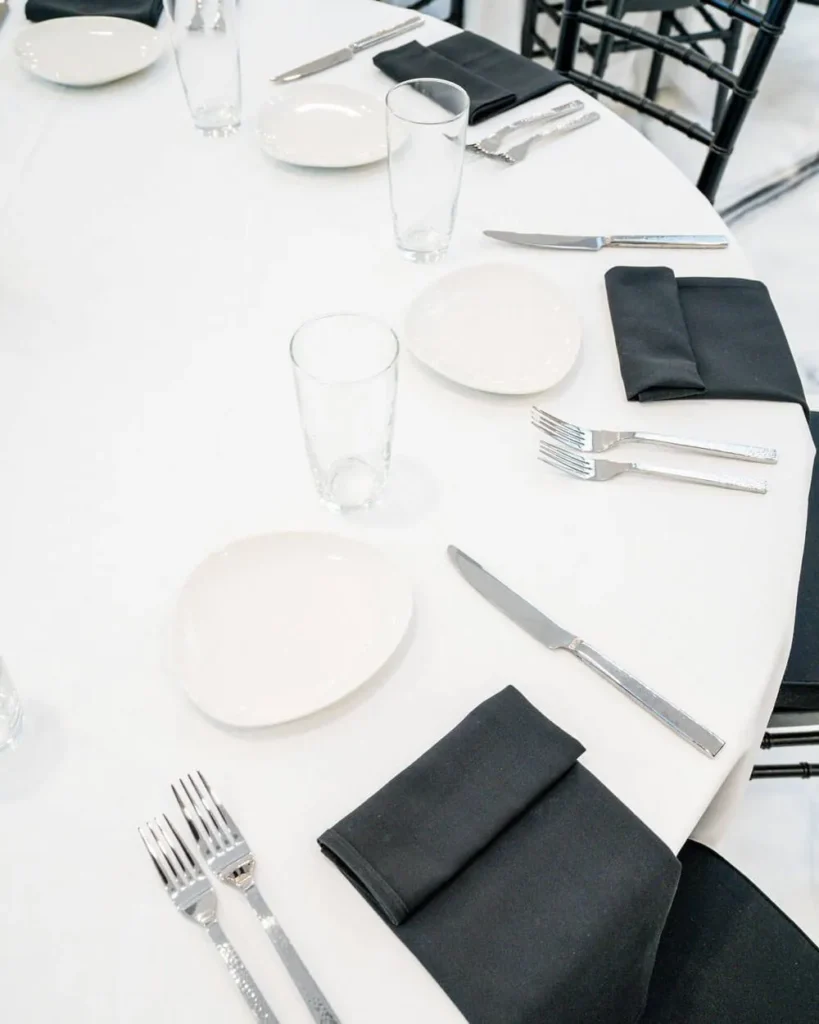 Round table set with place settings, napkins and glassware before a catered dinner service