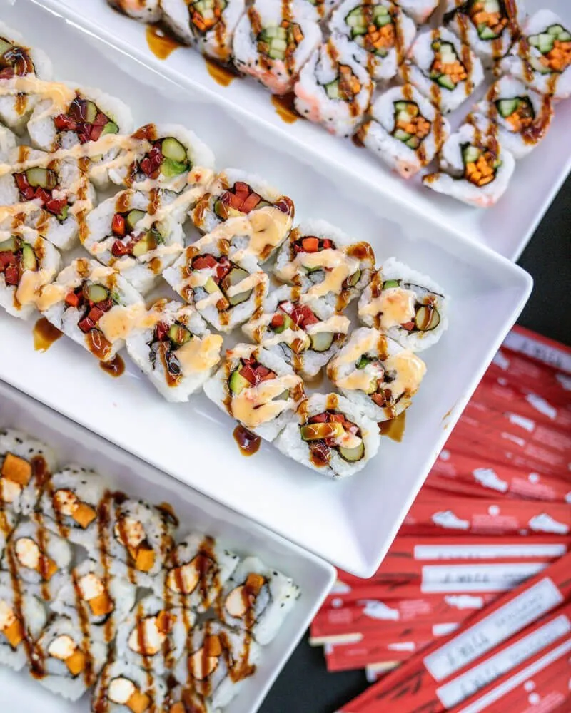 White platters of assorted sushi rolls arranged on a catering station at an event
