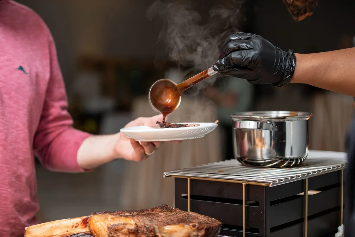 Chef spooning sauce onto a plate in a kitchen in Baltimore