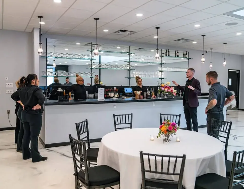 Event room with a service bar and a set round table as staff prepare in Baltimore