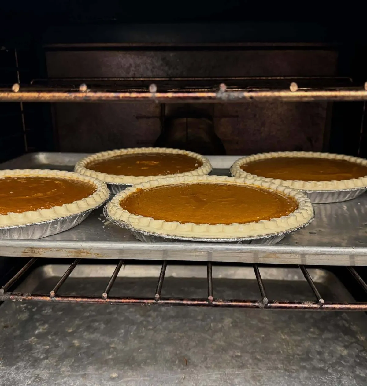 Pumpkin pies baking in a commercial oven during catering prep