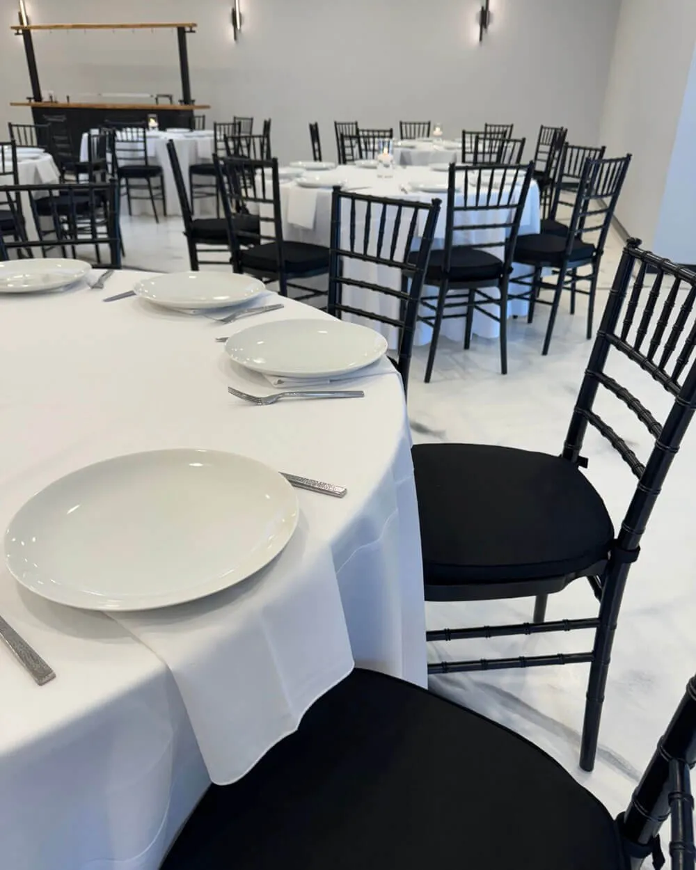 Dinner tables set with white linens and black chairs before a program in Baltimore