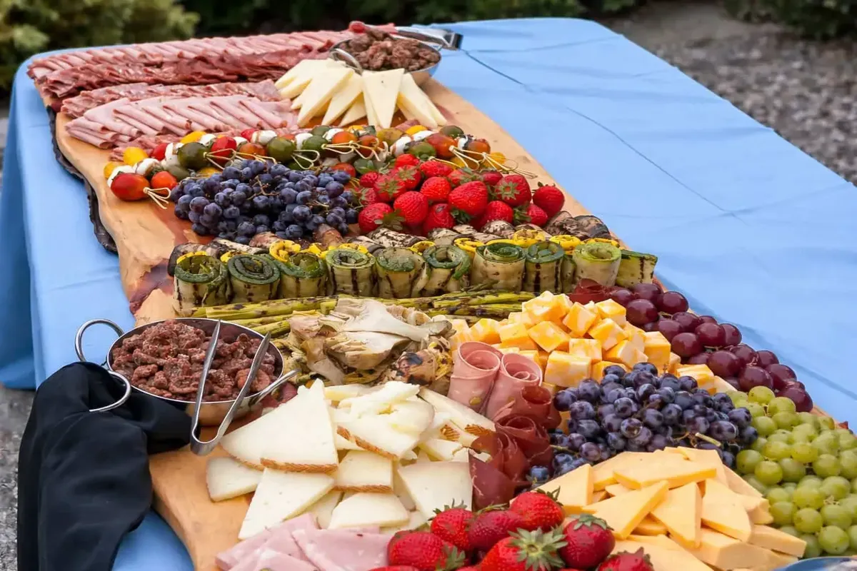 Outdoor grazing board of meats, cheeses, and fresh fruit set on a table for a catered event