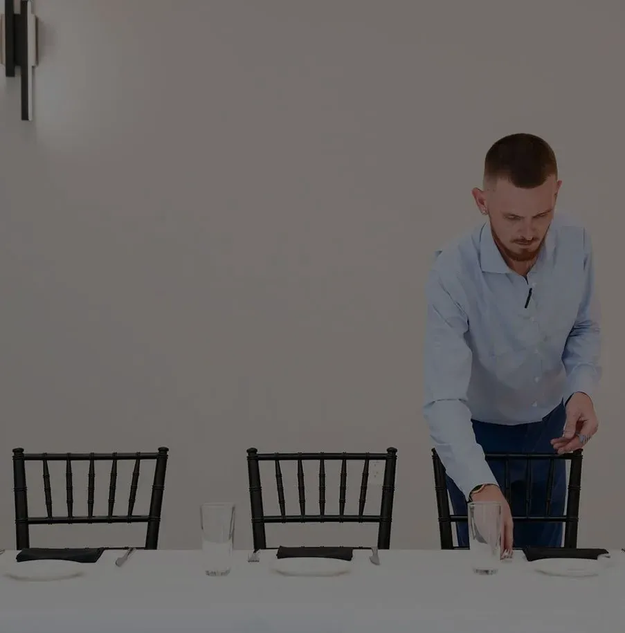 Staff member setting place settings at a table before an event in Baltimore