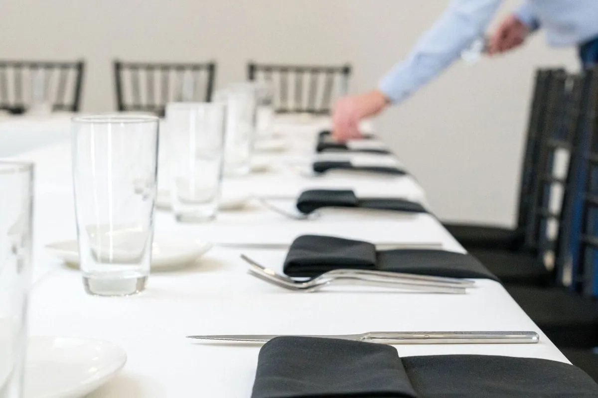 Catering staff setting glassware and napkins on a long event table in Baltimore